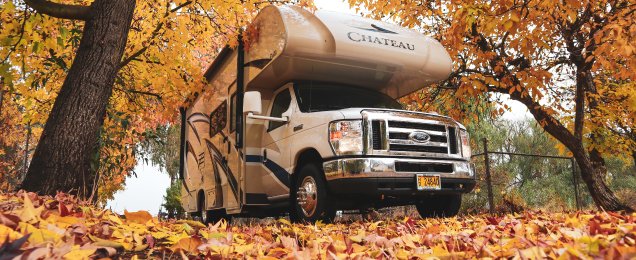 The image features a motorhome parked amidst a picturesque autumn setting. The vehicle is a 